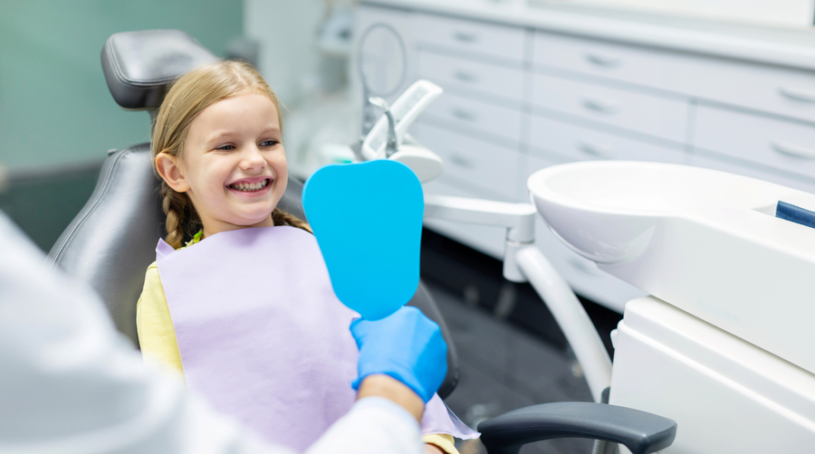 dentist-holding-mirror-showing-girl-her-healthy-teeth-dental-office-smiling-little-female copy.jpg